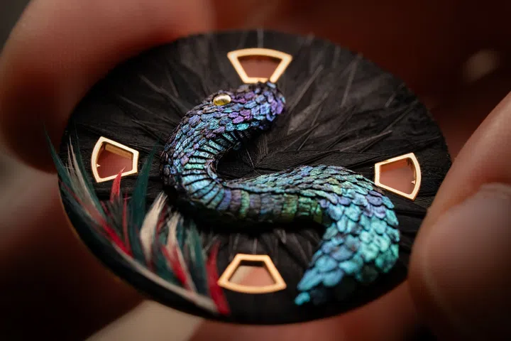Close-up of the Vacheron Constantin Feathersnake watch showing a serpent crafted from tiny feather pieces amid feathered green foliage.
