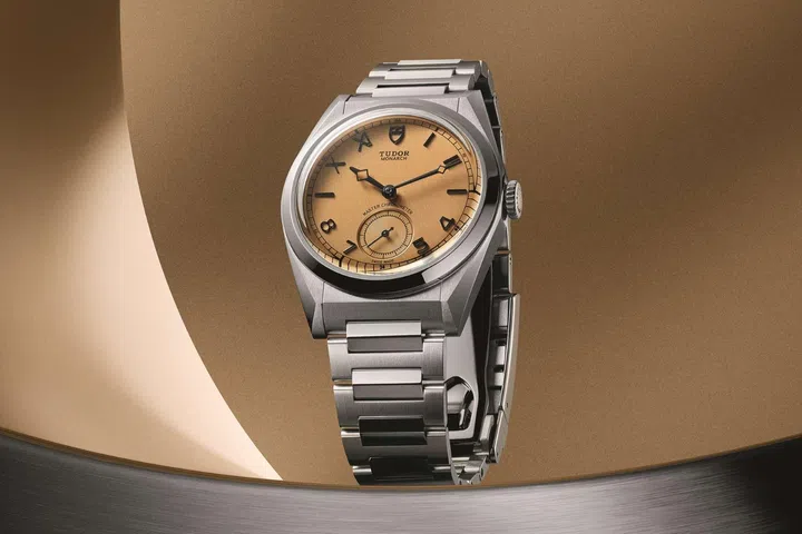 Tudor Monarch watch in a stainless steel case with integrated bracelet, featuring a vertically brushed papyrus-toned dial with mixed Roman and Arabic numerals.