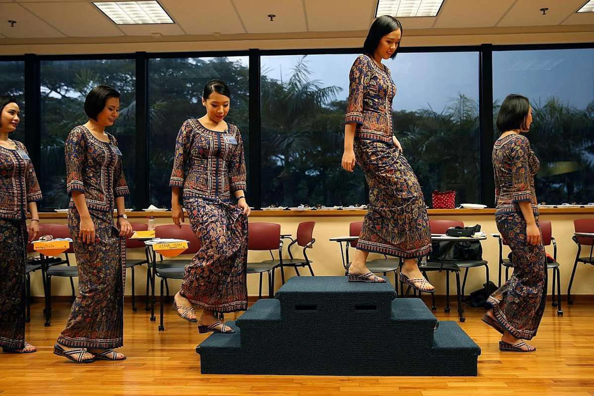 To uphold a positive and professional image of SIA, cabin crew trainees learn how to climb the stairs and walk gracefully in their kebayas during a deportment and etiquette class. Besides social and business etiquette, basic postures while standing, sitting, reaching and walking are also covered. <br><br>The distinctive kebaya uniform, designed by French couturier Pierre Balmain, was introduced in 1968. Tailor-made for every female cabin-crew member, trainees do the fitting during the first month of their training. 