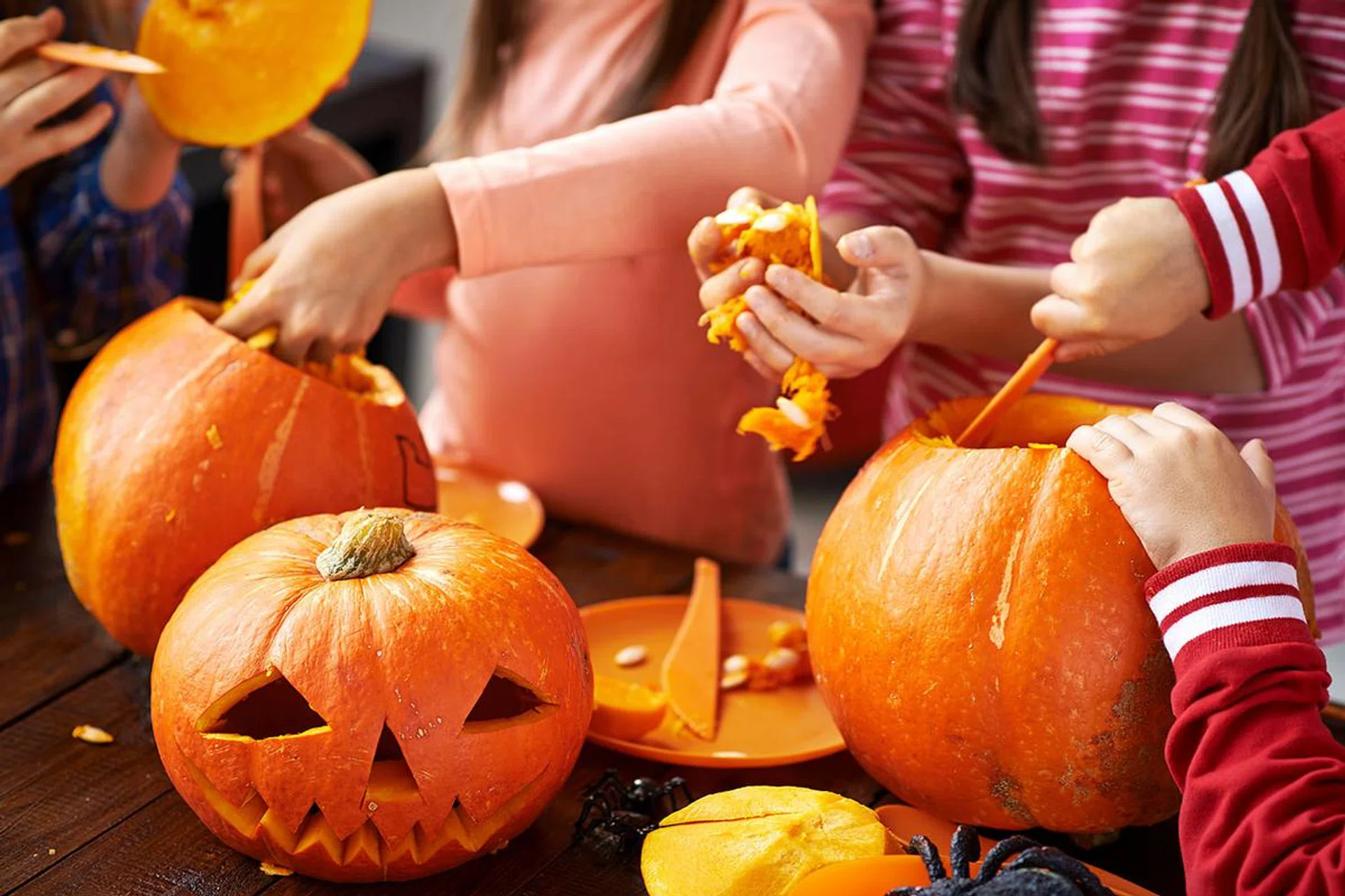 Children hollowing out a pumpkin to prepare Halloween lantern