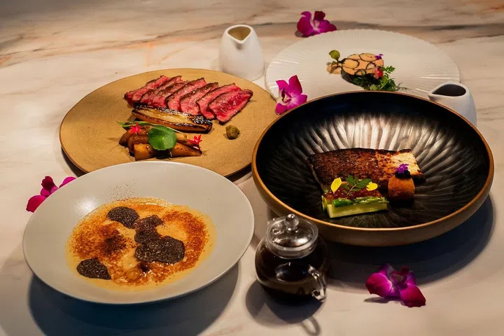 Camille's three course meal, with both appertisers, the Cèpe and Shiitake Cappuccino (left, front) and the Mosaic (right, back); both mains, the Argentinian Flat Iron Steak (left, back), and the White Miso Glazed Kuhlbarra Barramundi (right, front). (Image: 1-Flowerhill)