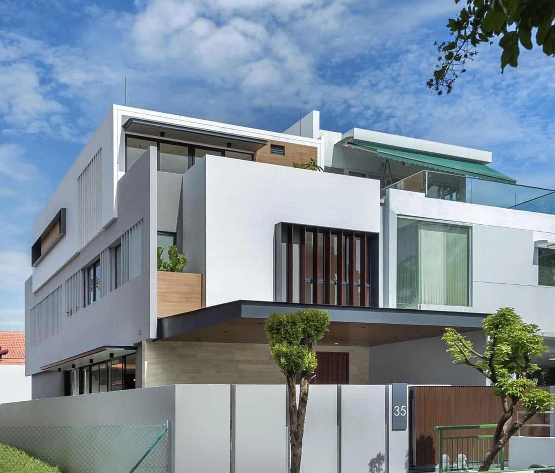 On the facade of the home, vertical fins provide privacy and help to shield the sun from the northwest direction that would otherwise shine into the grandparents’ room.

From the outside, one can also glimpse the timber textured walls and greenery that adorns the bathroom on the upper level. (Credits: 