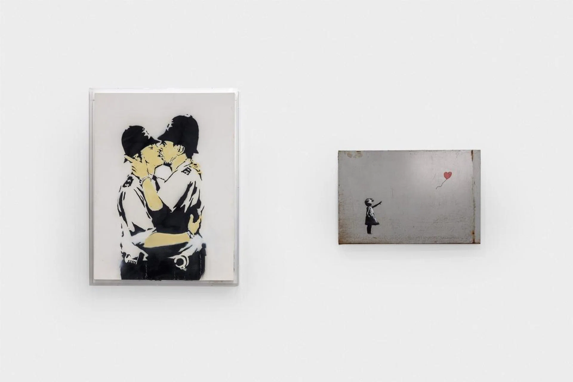 Banksy's Kissing Coppers (2005) and Girl with Balloon (2006) from the Robbie Williams collection auctioned by Sotheby's. (Photo credit: Joshua White/Sotheby's)