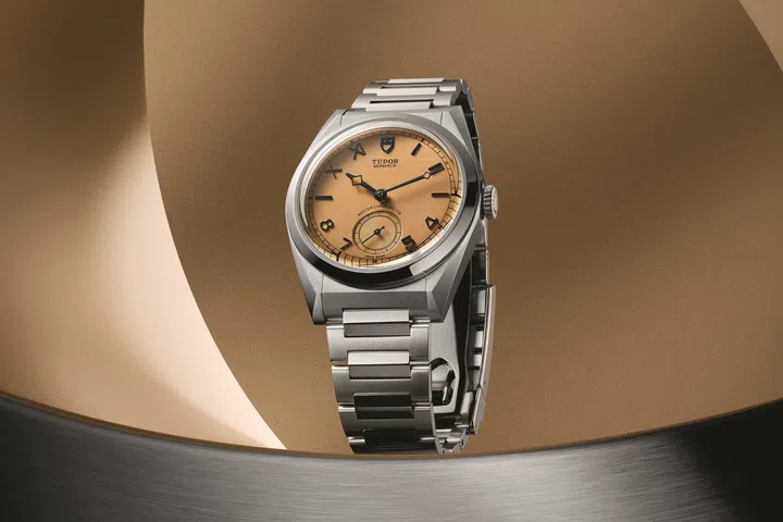 Front view of the Tudor Monarch featuring a 39mm stainless steel case and bracelet, vertically brushed papyrus-toned dial with Roman and Arabic applied hour markers, small seconds at 6 o’clock, and a faceted bezel.