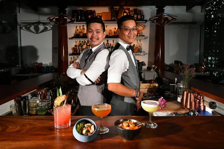 Bartenders Edwin Poh (top left) and Mark Tay serve locally inspired cocktails such as (from bottom left) The Lion City, Hainanese Chicken Rice, Katong Laksa and The Peranakan. ST PHOTO: LIM YAOHUI