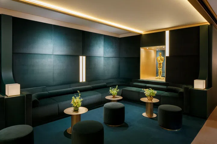 The Rolex-designed Oscars Greenroom featuring rich green velvet furnishings, champagne gold finishes, and portraits from Oscars history, with a gold Oscars statuette displayed prominently.