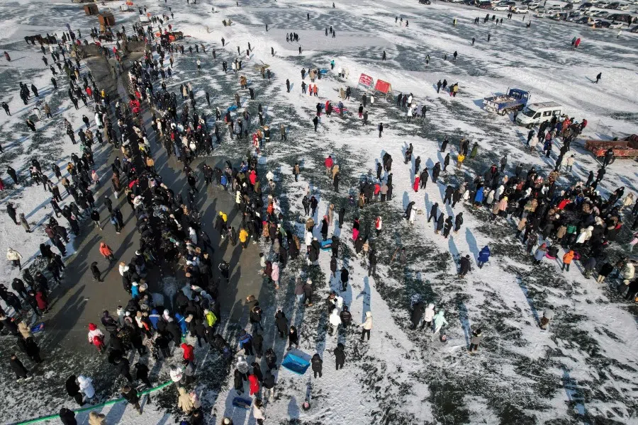 This aerial photo shows visitors watching as fishermen use a net placed under the ice to catch fish during the annual Chagan Lake Winter Fishing Festival in Songyuan, in northeast China's Jilin province on 28 December 2022. (Jade Gao/AFP)