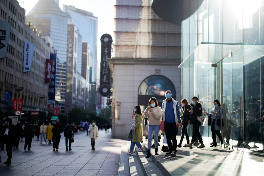 People wearing protective face masks walk on a street, following new cases of the coronavirus disease (Covid-19), in Shanghai, China, 23 December 2021. (Aly Song/Reuters)
