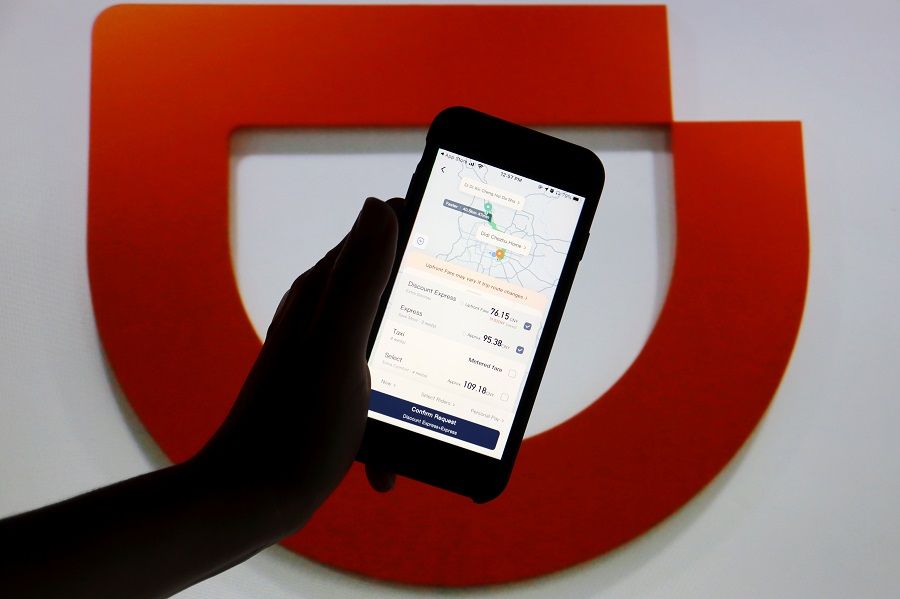 The app of Chinese ride-hailing giant Didi is seen on a mobile phone in front of the company logo displayed in this illustration picture taken on 1 July 2021. (Florence Lo/Illustration/File Photo/Reuters)