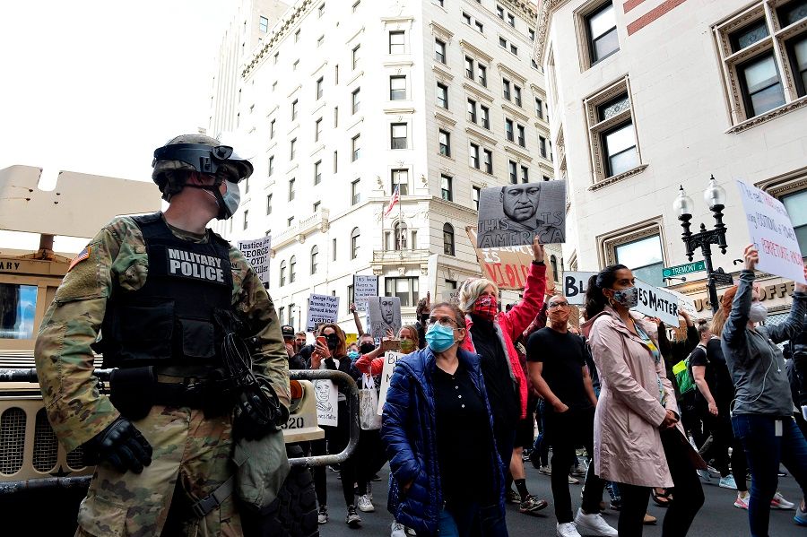 A National Guard soldier looks on as people march from Boston City Hall to just outside the Boston Police Station to call for Police Department reform as part of the "Unite Against Racist Police Terror! Boston Speakout and March" in Boston, Massachusetts on 7 June 2020. (Joseph Prezioso/AFP)