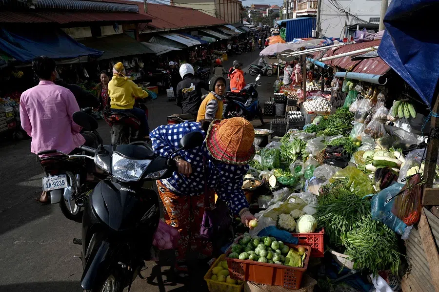 A woman buys vegetables at a market at Krong Saen Monourom in Mondulkiri province, Cambodia, on 17 January 2025. (Tang Chhin Sothy/AFP)