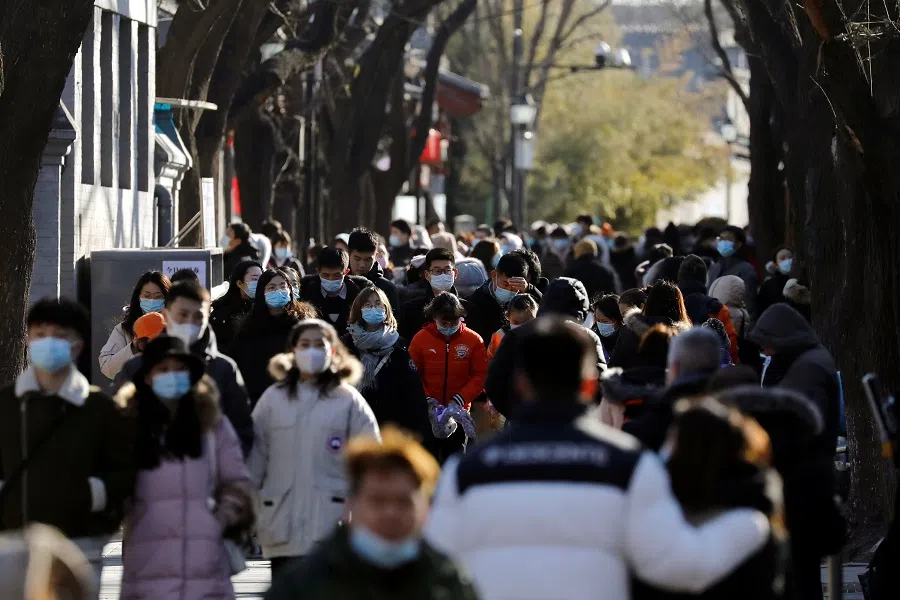 People wearing face masks walk along Nanluoguxiang alley, in Beijing, China, 16 January 2021. (Tingshu Wang/Reuters)