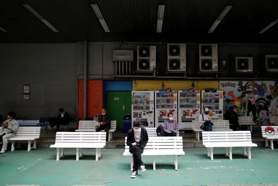 People practice social distancing on benches outside a shop in Tokyo, 9 May 2020. (Issei Kato/REUTERS)