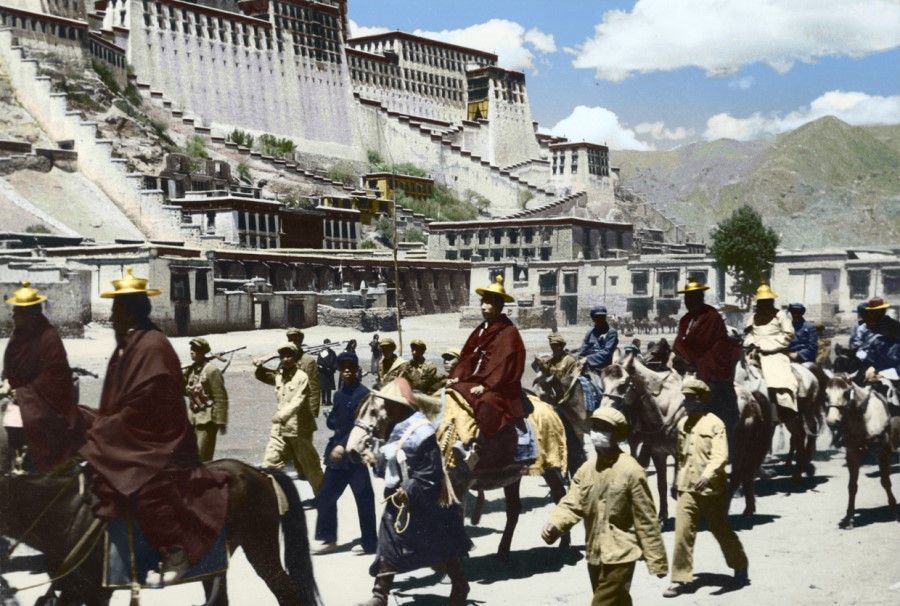 A procession of monks in front of Potala Palace, followed by PLA troops, 1951.