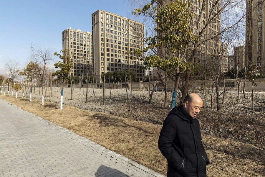 A pedestrian passes apartment buildings at the Magnolia Mansion residential project, developed by Sunac China Holdings Ltd., in Shanghai, China, 14 January 2022. (Qilai Shen/Bloomberg)