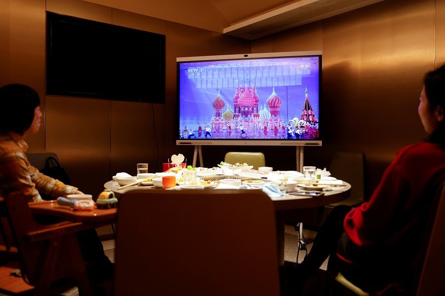 A family watches CCTV's New Year's Gala after having dinner at a Haidilao hotpot restaurant, in Beijing, China, 11 February 2021. (Carlos Garcia Rawlins/Reuters)