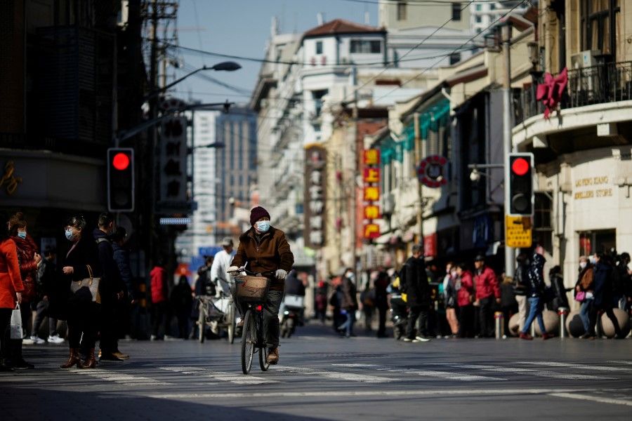 A man wearing a mask as a prevention against Covid-19 rides a bicycle on a crossroad, ahead of the annual National People's Congress (NPC), in Shanghai, China, 25 February 2022. (Aly Song/Reuters)