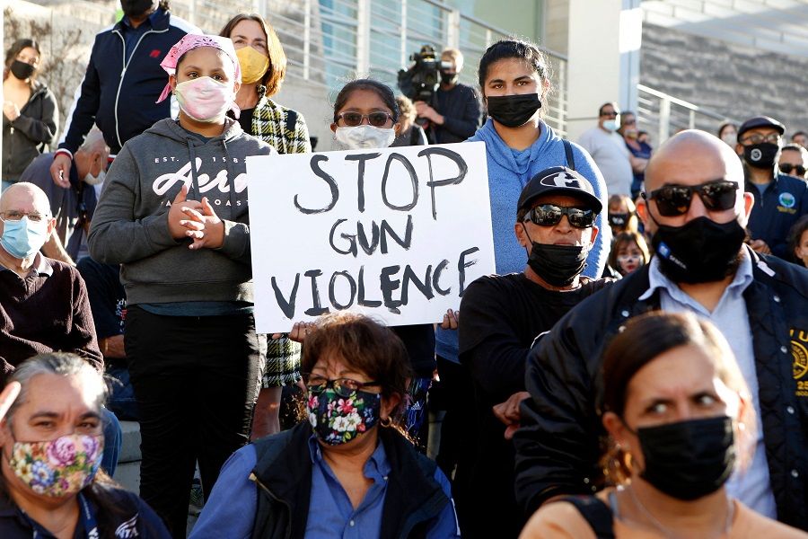 In this file photo, a girl holds a sign as people attend a vigil for the victims of a shooting at San Jose City Hall in San Jose, California on 27 May 2021. (Amy Osborne/AFP)