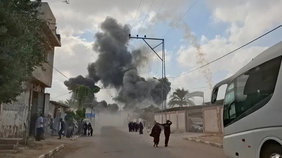 People run as plumes of smoke rise following an Israeli airstrike, amid the ongoing conflict between Israel and Hamas, in Deir al-Balah, Gaza Strip, on 21 August 2025, in this screen grab obtained from a video. (Video obtained by Reuters/Handout)