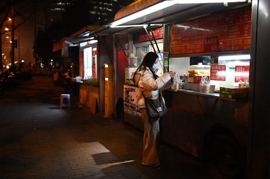 A commuter buys food at a food stall outside a subway station in Beijing on 18 December 2025. (Wang Zhao/AFP)