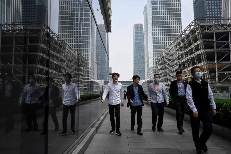 People walk past a construction site in the central business district of Beijing on 13 April 2022. (Jade Gao/AFP)