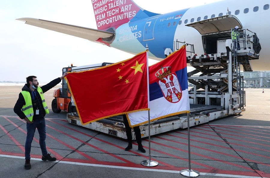 A man holds China's flag next to Serbia's flag as a plane transporting one million doses of Sinopharm's China National Biotec Group (CNBG) vaccines for the Covid-19 coronavirus arrives at Nikola Tesla Airport in Belgrade, Serbia, 16 January 2021. (Marko Djurica/Reuters)