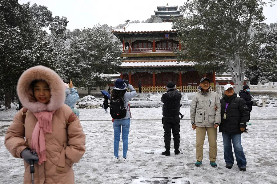 People enjoy snowfall at Jingshan Park, in Beijing, China, 7 November 2021. (Tingshu Wang/Reuters)