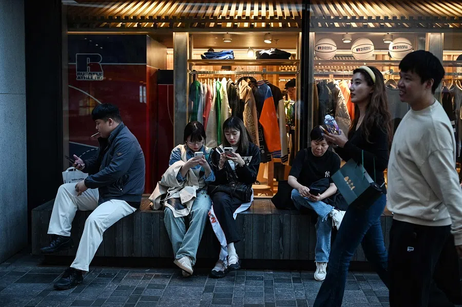 People rest outside a clothing store in a shopping mall during a week-long holiday marking China’s National Day, in Beijing on 4 October 2024.