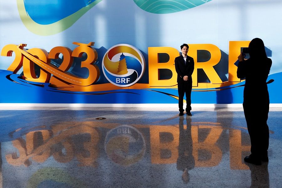 A staff member poses for pictures in front of a sign of the third Belt and Road Forum in Beijing, China, on 18 October 2023. (Tingshu Wang/Reuters)