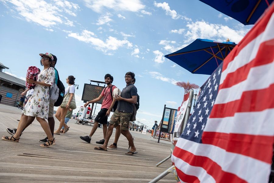 People walk on the Coney Island boardwalk on 4 September 2021 in the Brooklyn borough of New York City, US. (Alexi J. Rosenfeld/Getty Images/AFP)
