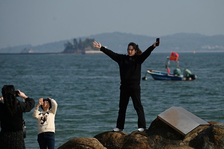 A woman poses with the backdrop of Taiwan's Kinmen Island, on the beach in Xiamen, in China's southeast Fujian province on 10 January 2024. (Greg Baker/AFP)