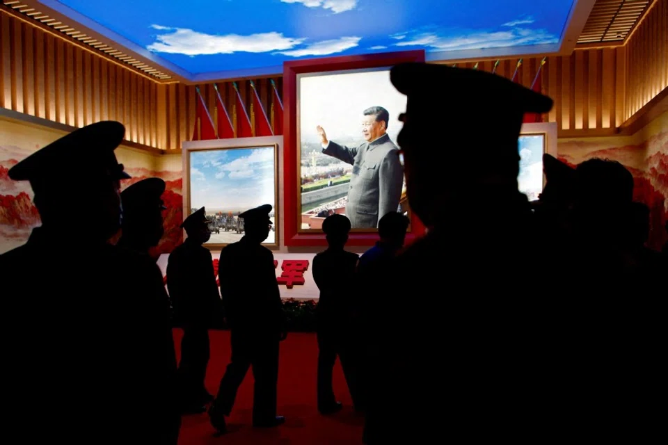 Members of the Chinese People's Liberation Army (PLA) walk past an image of Chinese President Xi Jinping at an exhibition at the Military Museum of the Chinese People's Revolution in Beijing, China, 8 October 2022. (Florence Lo/Reuters)