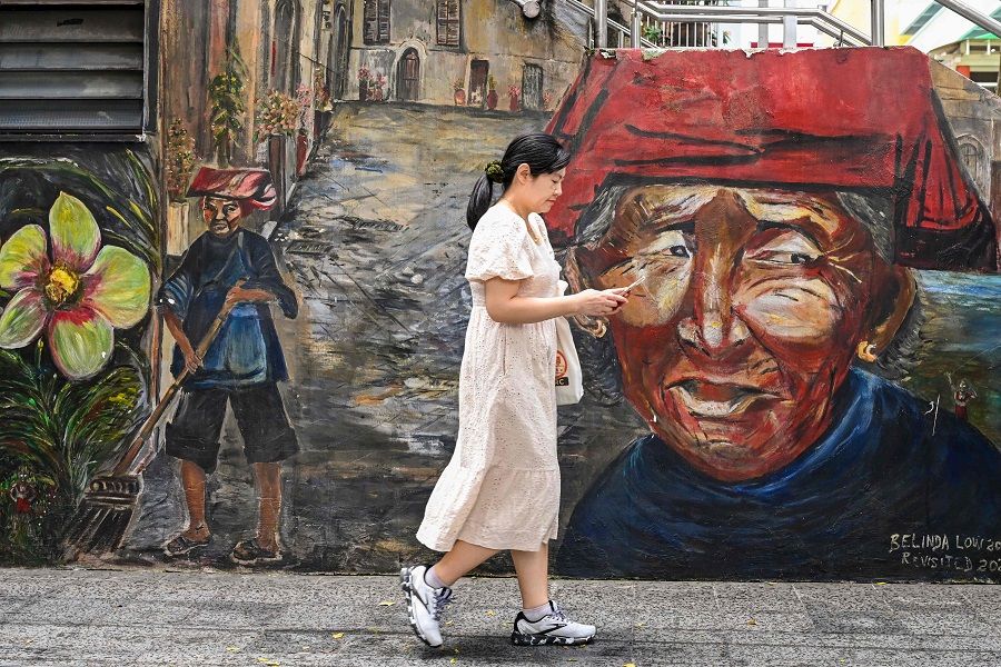 A woman walks past a mural in Chinatown in Singapore on 26 January 2024. (Photo by Roslan Rahman/AFP)