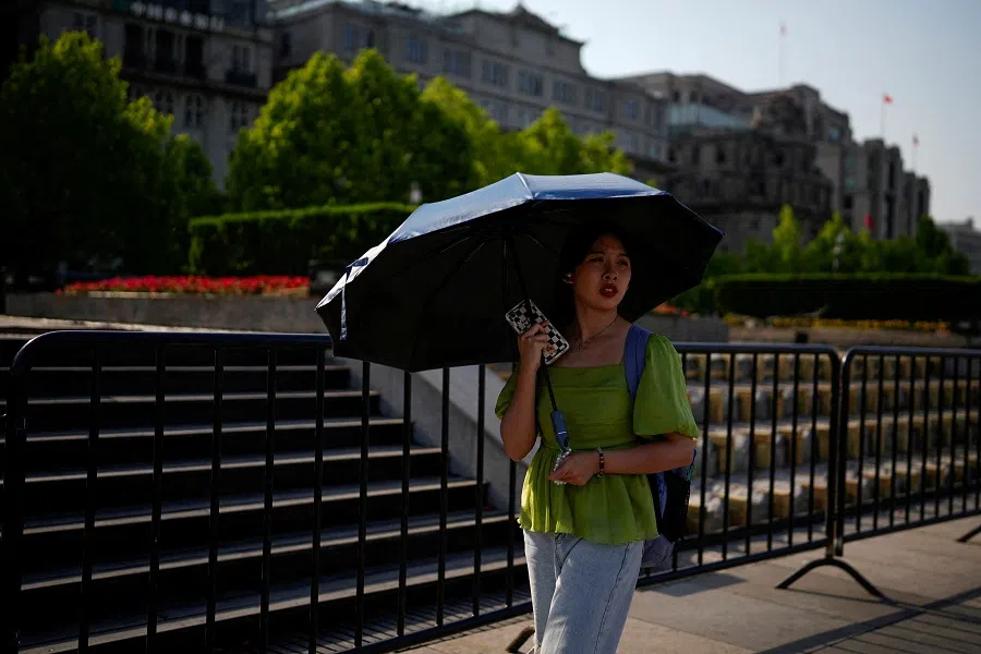 A woman uses an umbrella to protect herself from the sun as she walks on the Bund on a hot day, in Shanghai, China, on 15 May 2023. (Aly Song/Reuters)