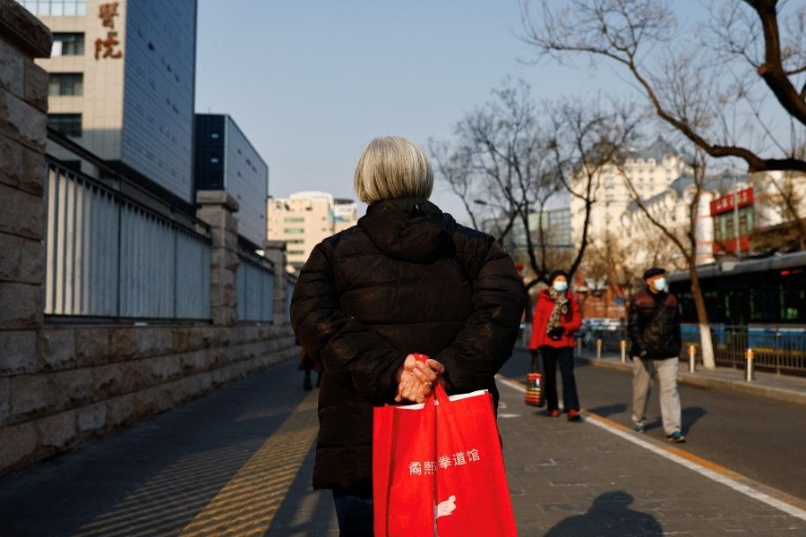 An elderly person walks near a hospital in Beijing, China, 16 February 2023. (Tingshu Wang/Reuters)