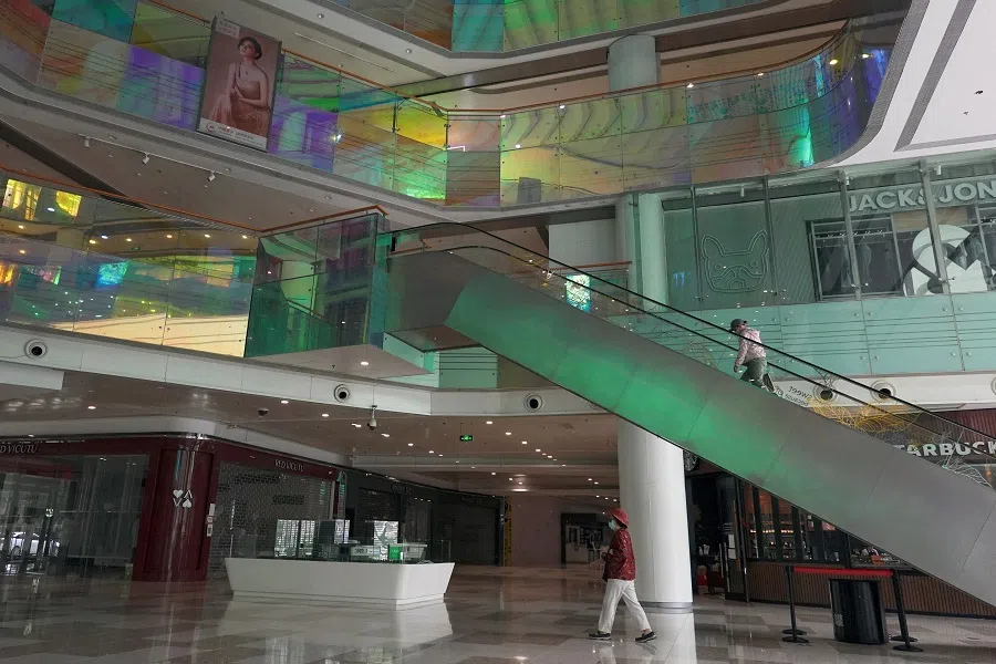 People walk inside a shopping mall where most shops are closed, amid the Covid-19 outbreak in Beijing, China, 9 May 2022. (Thomas Suen/Reuters)