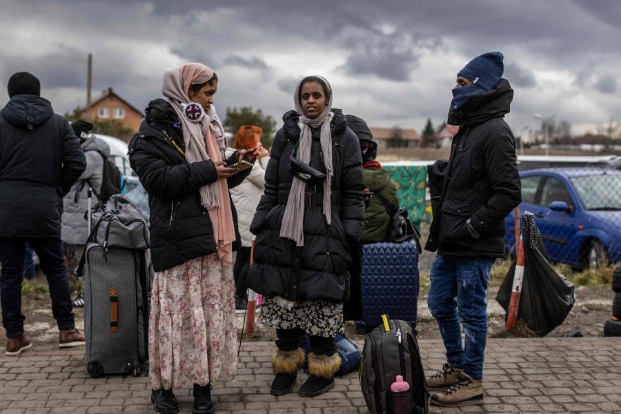 Indian girls wait for transport as refugees from many different countries - from Africa, Middle East and India - mostly students of Ukrainian universities arrive at the Medyka pedestrian border crossing fleeing the conflict in Ukraine, in eastern Poland on 27 February 2022. (Wojtek Radwanski/AFP)