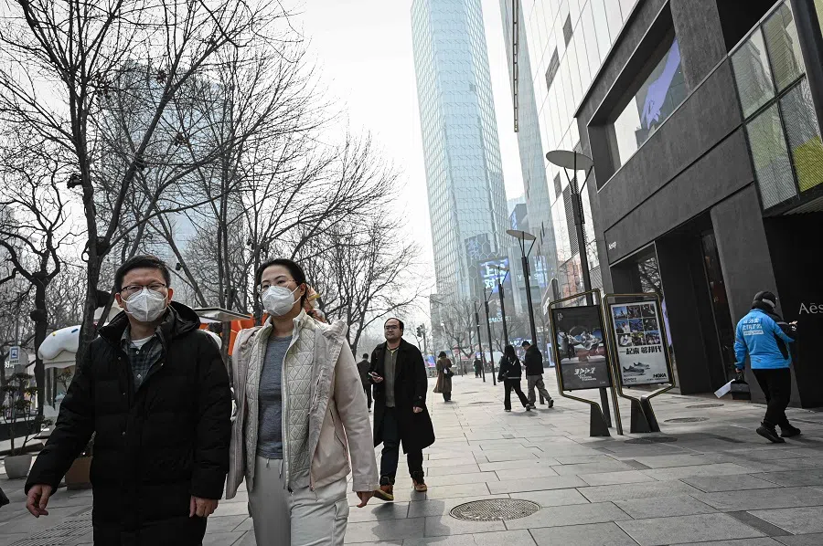 People walk past a shopping mall complex during a polluted day in Beijing on 1 March 2025. (Jade Gao/AFP)