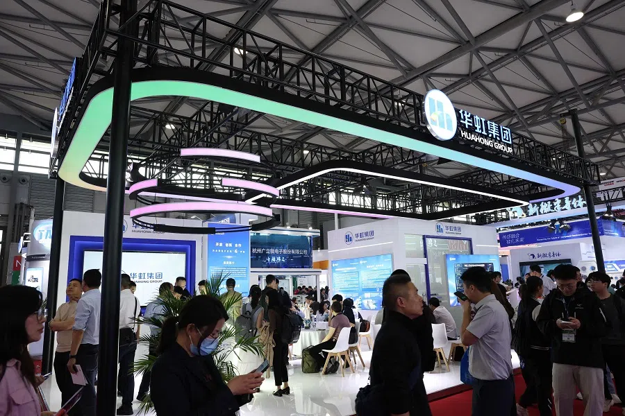 People walk through the Hua Hong Group stand at the SEMICON China semiconductor exhibition in Shanghai, China on 26 March 2025. (AFP)