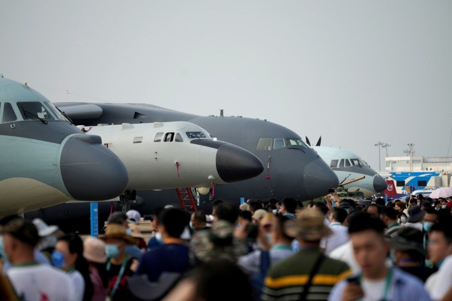 Visitors walk past military aircraft displayed at Airshow China, in Zhuhai, Guangdong province, China, 29 September 2021. (Aly Song/Reuters)