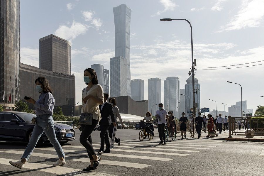 Pedestrians wearing protective masks walk across a road in the central business district in Beijing, China on 27 May 2021. (Qilai Shen/Bloomberg)