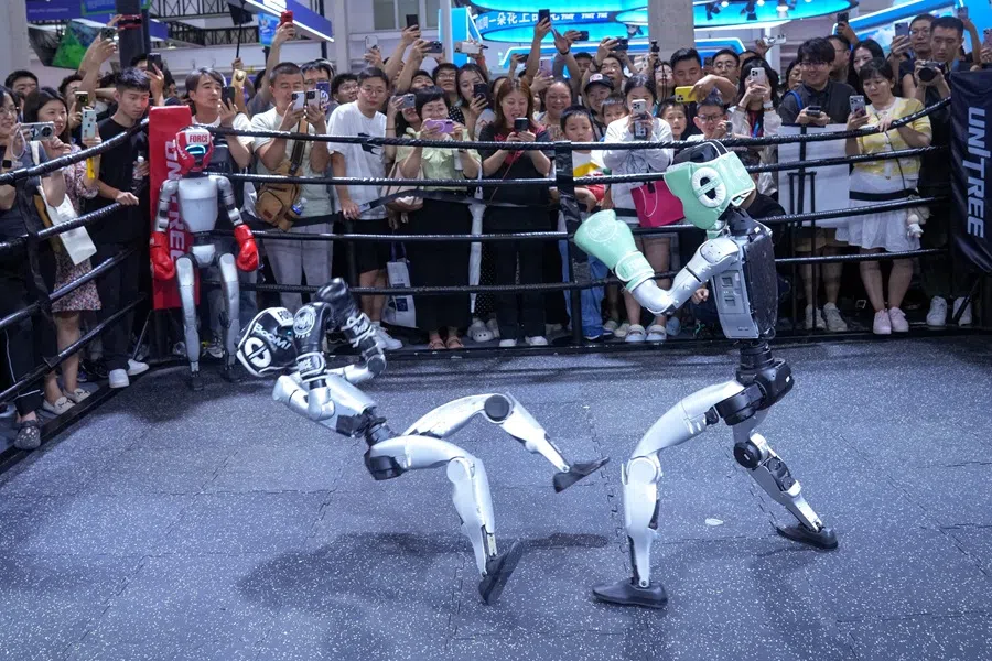 Visitors watch humanoid robots fight at the Unitree Robotics booth during the World Robot Conference in Beijing, China, on 8 August 2025.