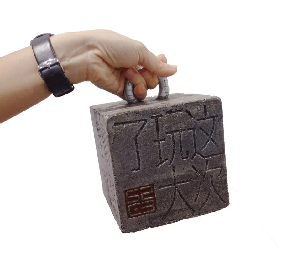 Artist Soh Suan Cheok carved a cement block for his work, 压死你 ("crushing you to death").