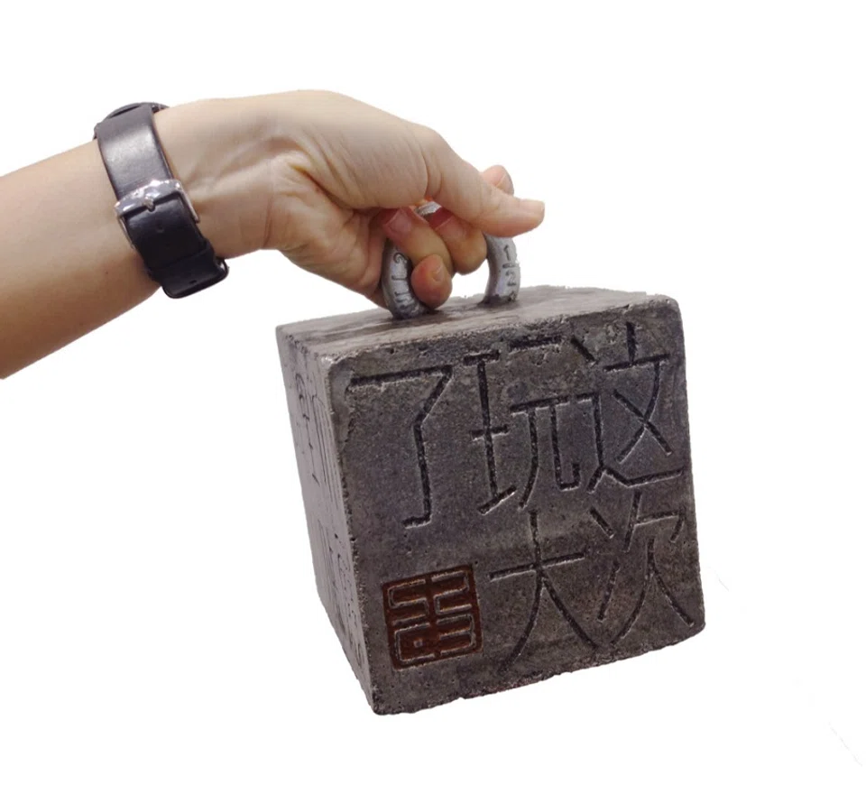 Artist Soh Suan Cheok carved a cement block for his work, 压死你 ("crushing you to death").