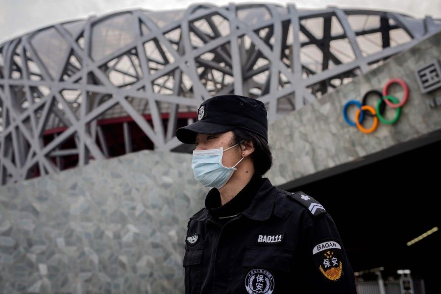 A security guard wearing a face mask amid the Covid-19 pandemic, stands guard at the site of the 2008 Beijing Olympics, in Beijing on 24 March 2020. (Nicolas Asfouri/AFP)