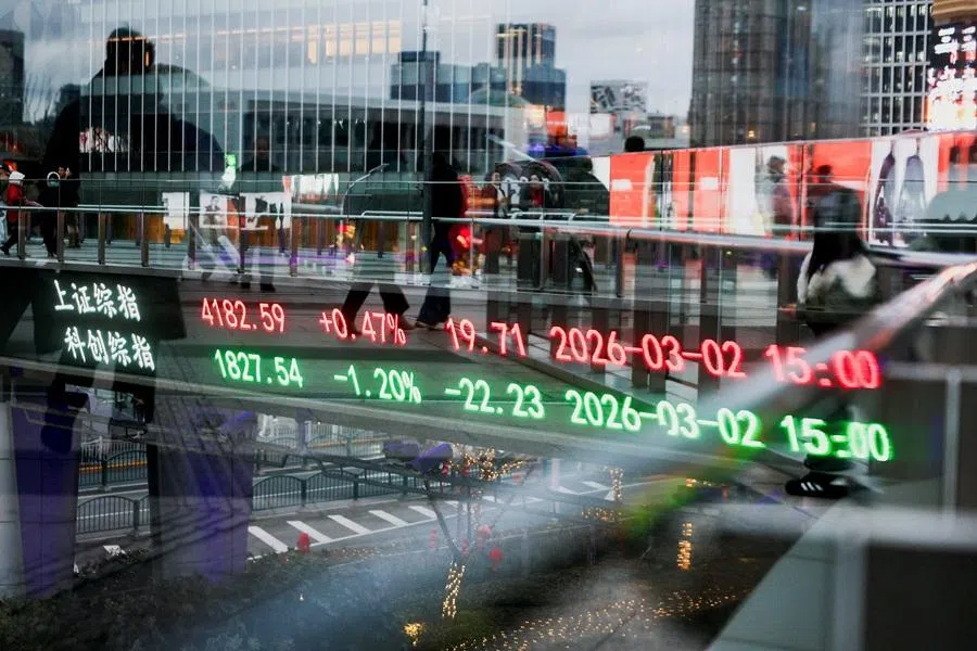 An electronic board shows Shanghai stock indices as people walk on a pedestrian bridge in the Lujiazui financial district in Shanghai, China, on 2 March 2026. (Go Nakamura/Reuters)