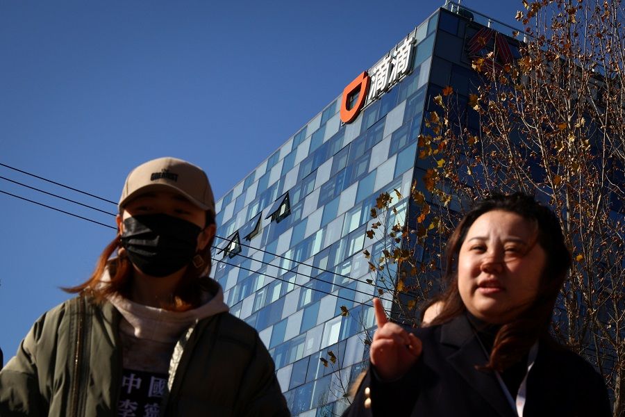 People walk past the headquarters of the Chinese ride-hailing service Didi in Beijing, China, 3 December 2021. (Thomas Peter/Reuters)