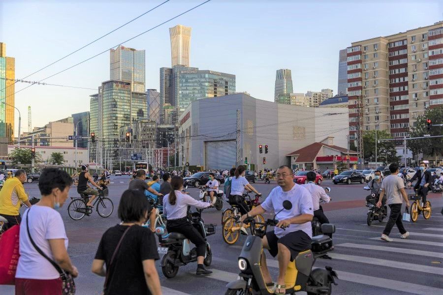 Commuters cross a traffic intersection in Beijing, China on 25 August 2021. (Qilai Shen/Bloomberg)