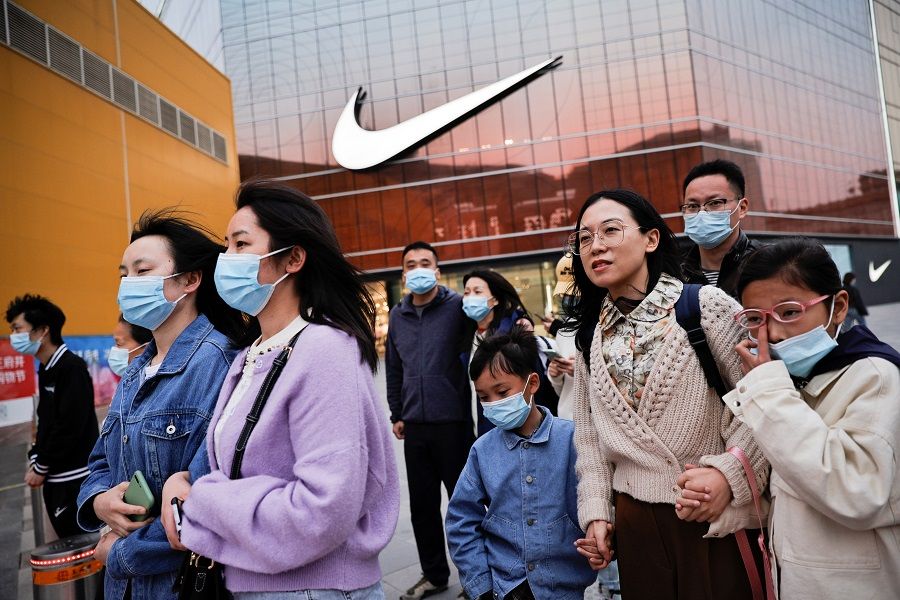 People walk in a shopping district in Beijing, China, 5 April 2021. (Thomas Peter/Reuters)