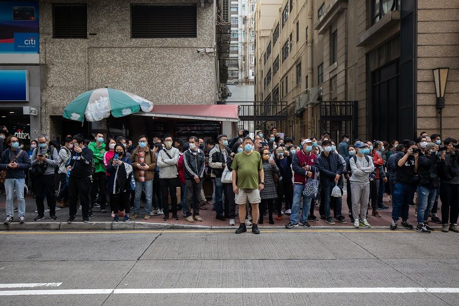 Bystanders watch across from a building that houses the office of online media outlet Stand News during a police raid in Hong Kong, China, on 29 December 2021. (Paul Yeung/Bloomberg)